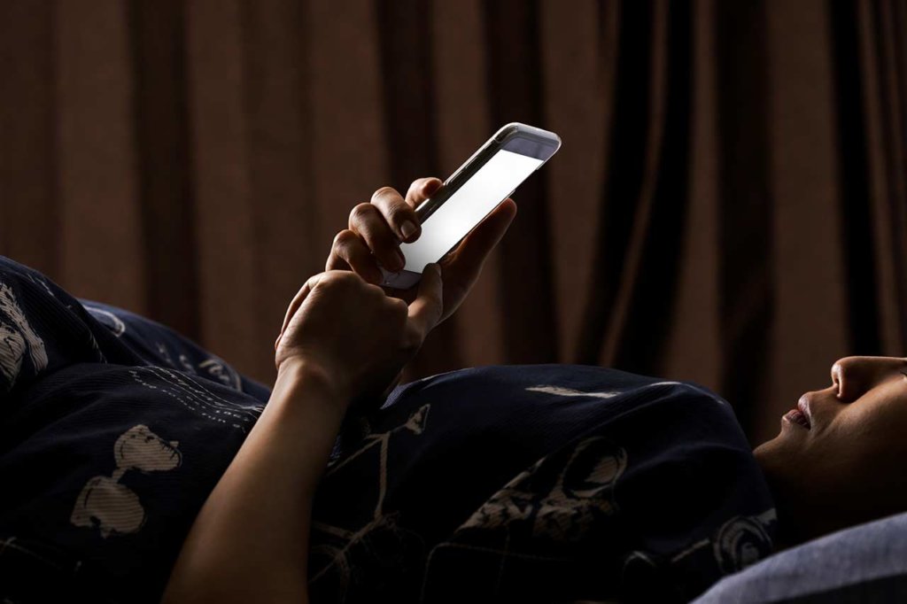 不眠でスマホを見る女性